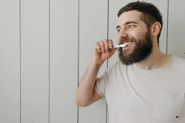 Hombre cepillándose los dientes como parte de su rutina de higiene bucal.