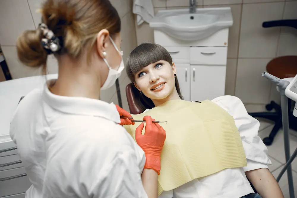 Odontólogo evaluando los dientes de una paciente durante una consulta dental